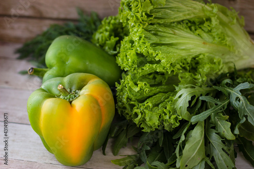 The concept of healthy eating. Green dill leaves and arugula, and lettuce along with green bell pepper on a wooden background