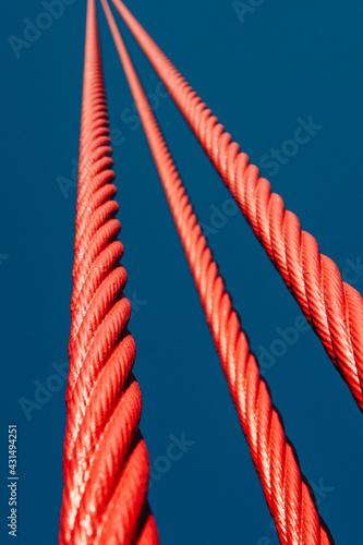 Close up shot of the red shiny steel cables of the famous Golden Gate bridge with a clear blue sky background, San Francisco, California, United States of America aka USA