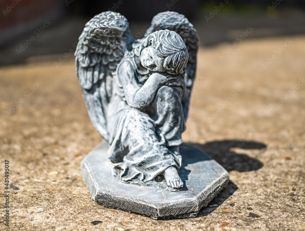 Close and selective focus of an angel statuette in a private back yard with intentional shallow depth of field and bokeh Close and selective focus of an angel statuette in a private back yard with intentional shallow depth of field and bokeh