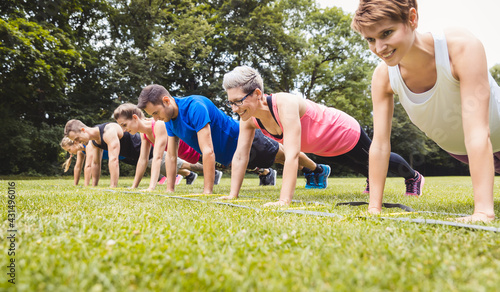 Fitness group practising push-ups in park