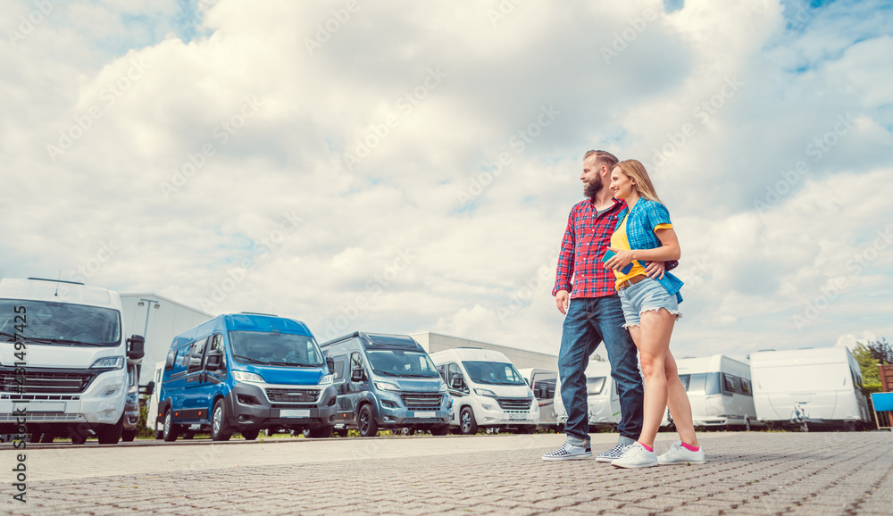 Fototapeta premium Woman and man choosing camper van to rent or buy