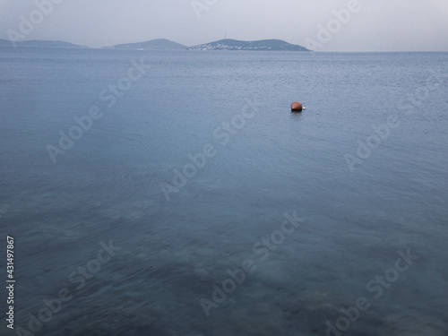 An orange buoy on the sea surface of Marmara, Istanbul. Princes' Islands are visible behind the background.
