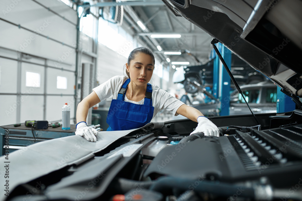 Female mechanic checks engine, car service Female mechanic checks engine, car service