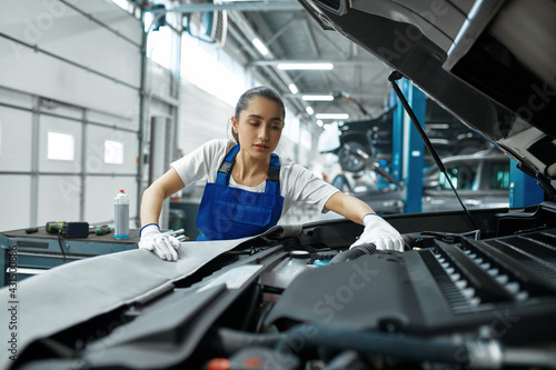 Female mechanic checks engine, car service