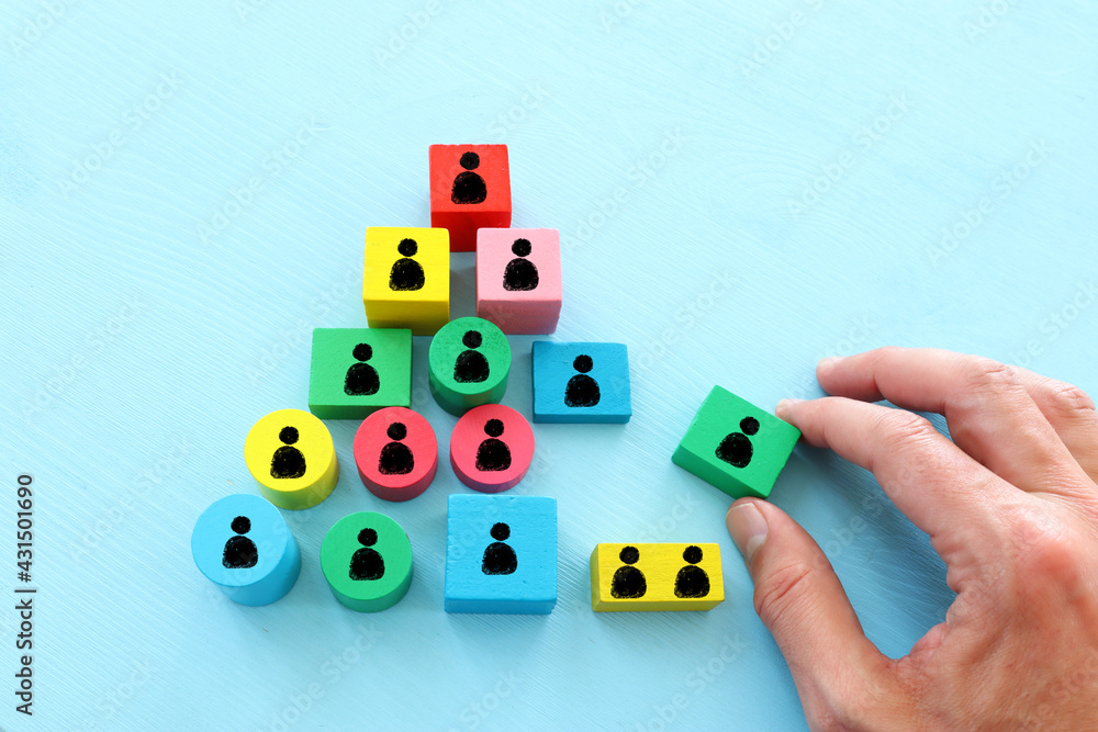 Obraz premium image of tangram puzzle blocks with people icons over wooden table ,human resources and management concept