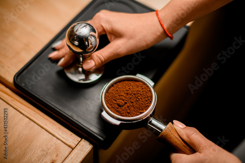 Close-up of barista hand tamping coffee in portafilter before making fresh drink