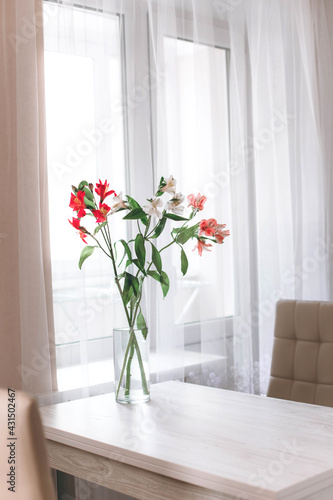 At the kitchen. bouquet of flowers in glass vase on the wooden table. 
