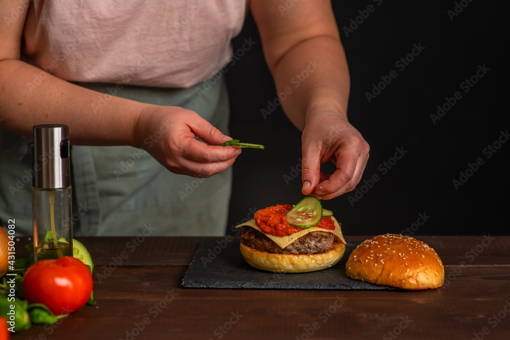 Close-up on the preparation of a magnificent burger.  Gastronomy, recipes, menus, fast food. Juicy hamburger