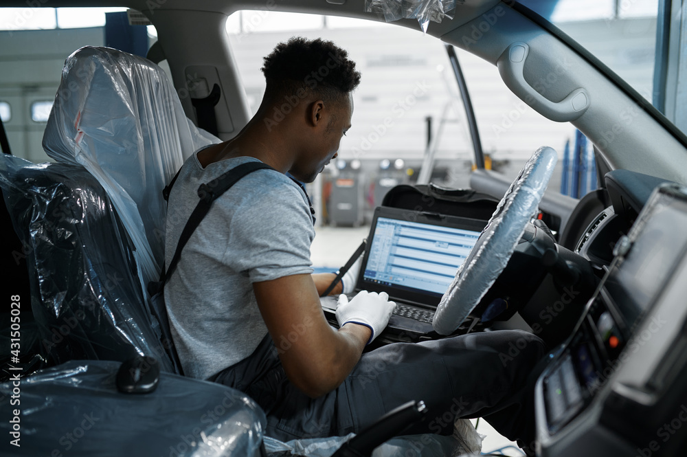 Male mechanic using laptop, car service Male mechanic using laptop, car service
