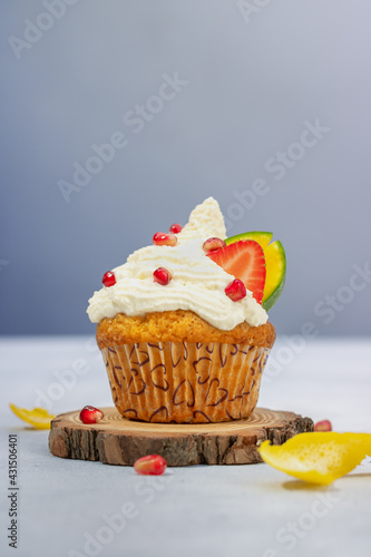 Lemon muffin with whipped cream and fruit. Lemon cupcake with whipped cream, melon, mango and pomegranate. Fairytale colors. Homemade pastries. Baking at home. Culinary hobby.