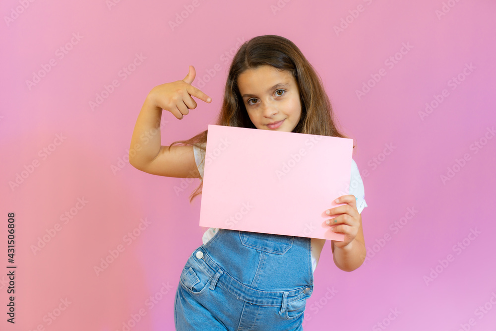 Smiling little girl holding empty pink board isolated over pink background. Smiling little girl holding empty pink board isolated over pink background.