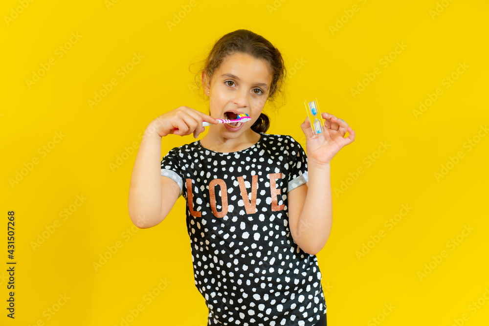 Cute little girl brushing teeth, isolated over yellow background Cute little girl brushing teeth, isolated over yellow background