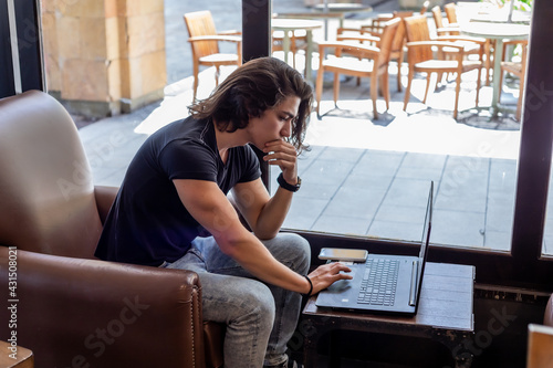 hombre joven trabajando online vía laptop y celular