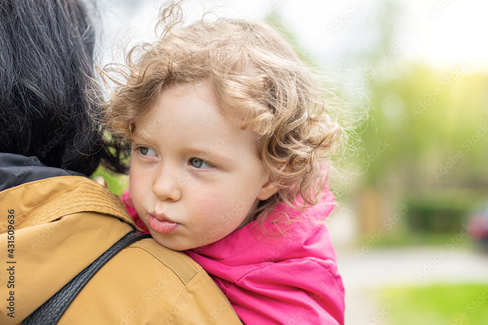 A sad child in her mother's arms.