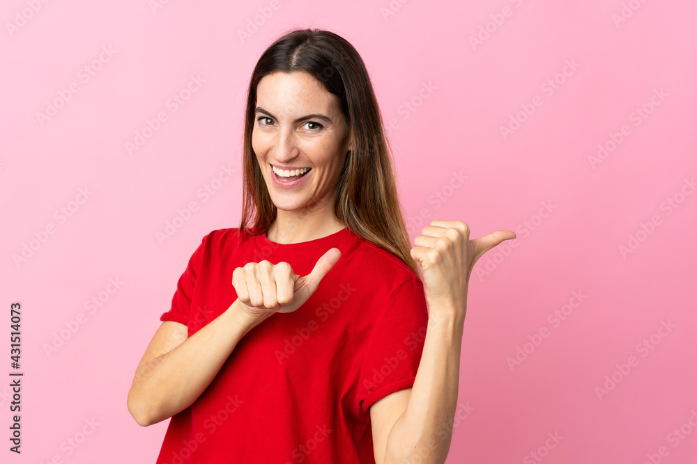 Young caucasian woman isolated on pink background pointing to the side to present a product Young caucasian woman isolated on pink background pointing to the side to present a product