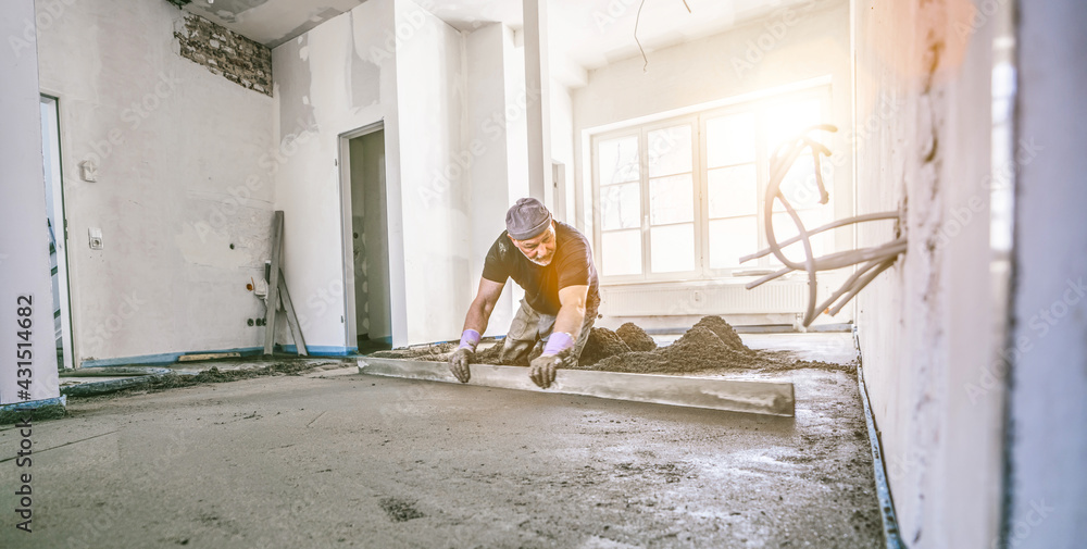 Filling the floor of a renovated apartment with concrete, screed and leveling the floor by construction workers. Even floors made of a mixture of cement, industrial concreting. Bright sun shine
