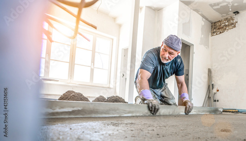 Valokuva Filling the floor of a renovated apartment with concrete, screed and leveling the floor by construction workers