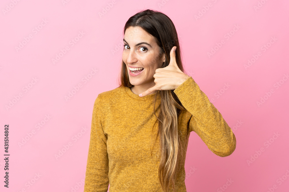 Young caucasian woman isolated on pink background making phone gesture. Call me back sign Young caucasian woman isolated on pink background making phone gesture. Call me back sign