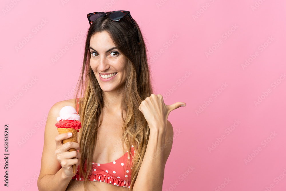 Young caucasian woman holding an ice cream isolated on pink background pointing to the side to present a product Young caucasian woman holding an ice cream isolated on pink background pointing to the side to present a product