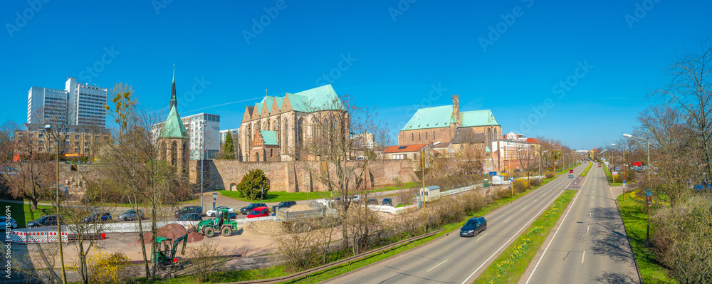 Panoramic view of Maria Magdalena Chapel, Saint Petri Church and Evangelical Church at Spring near highway with cars in Magdeburg historical downtown, Germany, at sunny day and blue sky.