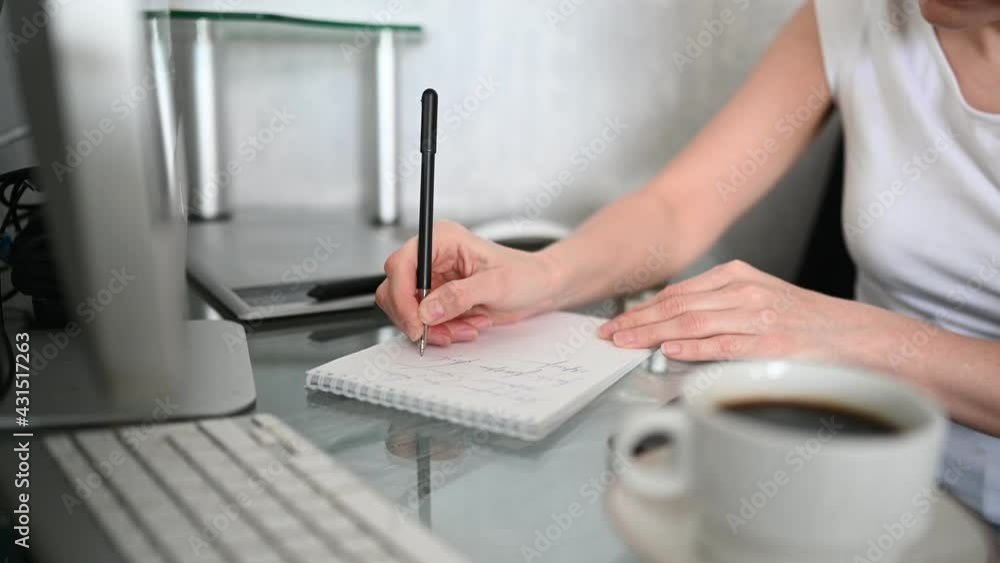close up hands of unrecognizable woman student sitting in front of computer with coffee learns online writes notes in notebook working at home office. Remote distance work education close up hands of unrecognizable woman student sitting in front of computer with coffee learns online writes notes in notebook working at home office. Remote distance work education
