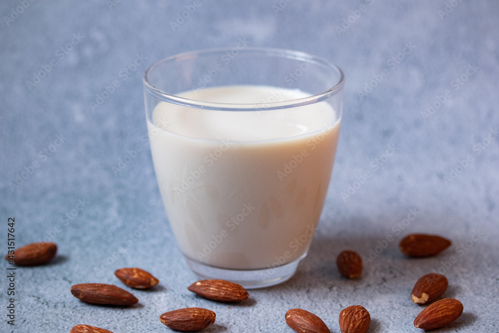 Almond milk in a clear glass on a gray background Almond milk in a clear glass on a gray background