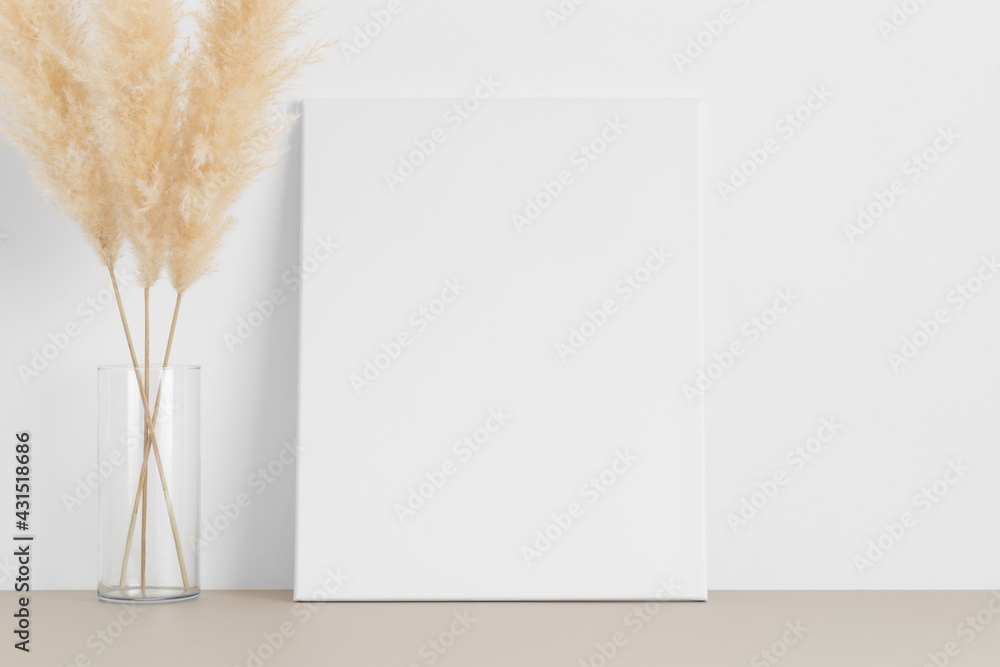 White canvas mockup with a pampas on the beige table. White canvas mockup with a pampas on the beige table.