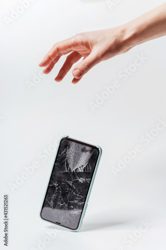 Smartphone falling out of hand on a white background. Crash protective tempered glass for smartphone. Smartphone with broken screen falls out of hand