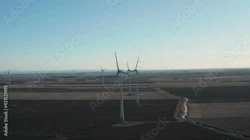 drone approaching some wind turbines by the front of the turbines and showing the rest of the wind farm photo