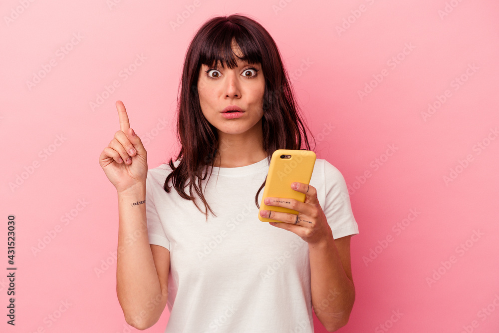 Young caucasian woman holding a mobile phone isolated on pink background having some great idea, concept of creativity. Young caucasian woman holding a mobile phone isolated on pink background having some great idea, concept of creativity.