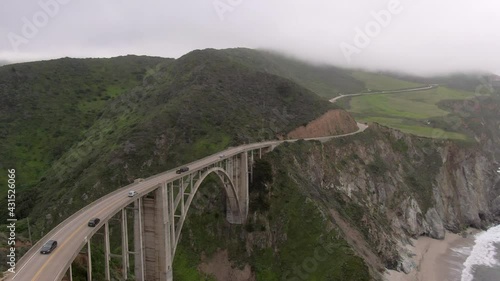 Aerial Shot Of Vehicles On Famous Bixby Creek Bridge Over Cliff, Drone Flying Forward Towards Mountains Under Fog - Big Sur, California