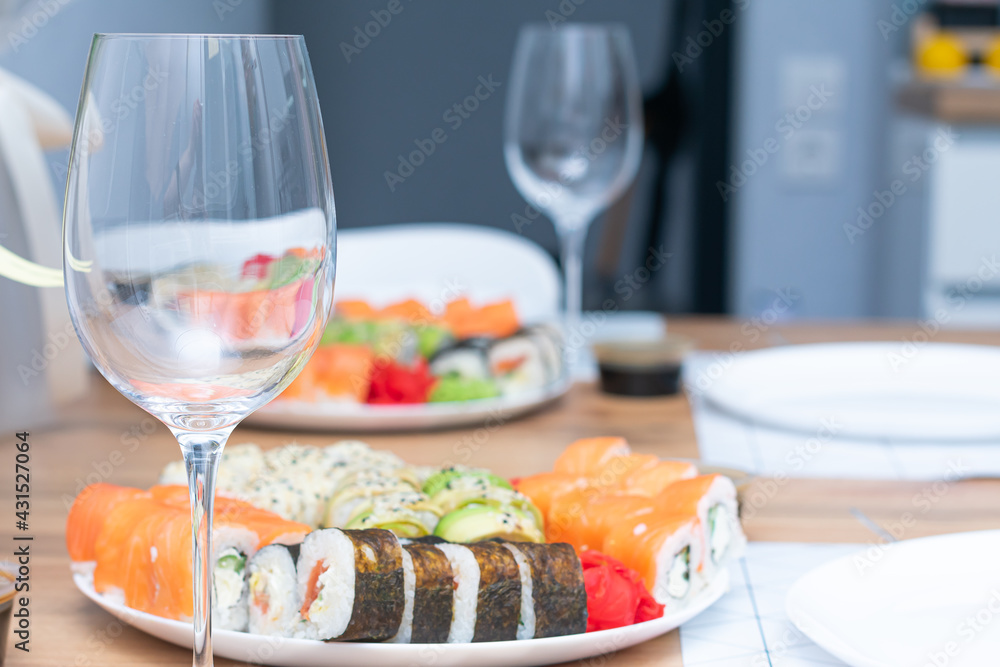 Delicious japanese rolls on a plate on the table and a glass of wine