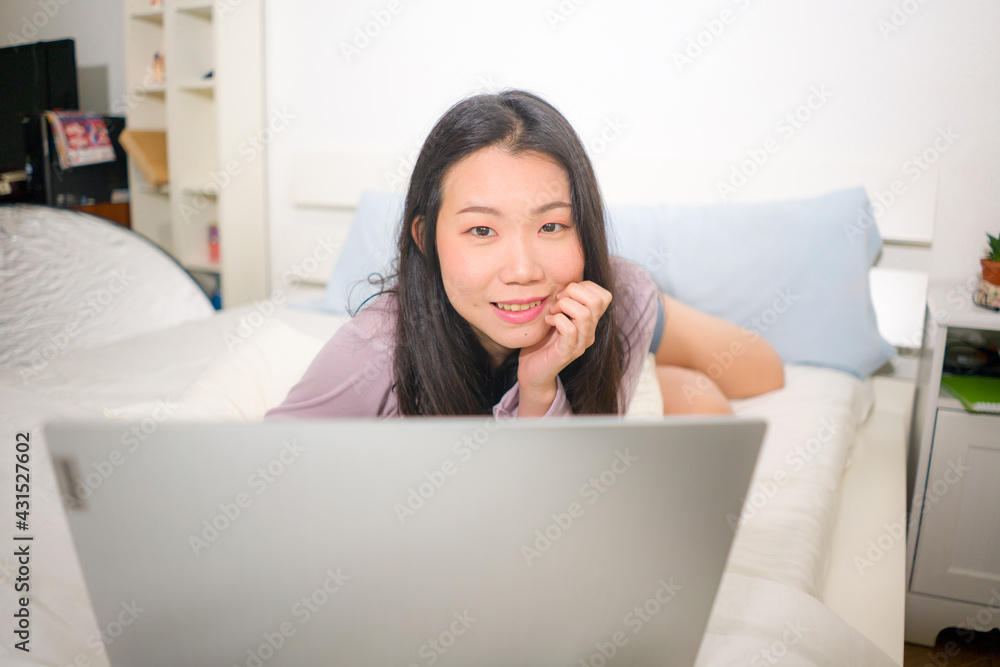 home lifestyle portrait of young Asian woman networking on bed - beautiful and happy Chinese girl in bedroom using laptop computer smiling relaxed and cheerful home lifestyle portrait of young Asian woman networking on bed - beautiful and happy Chinese girl in bedroom using laptop computer smiling relaxed and cheerful