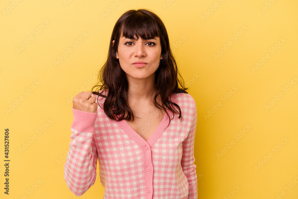 Young caucasian woman isolated on yellow background showing fist to camera, aggressive facial expression. Young caucasian woman isolated on yellow background showing fist to camera, aggressive facial expression.