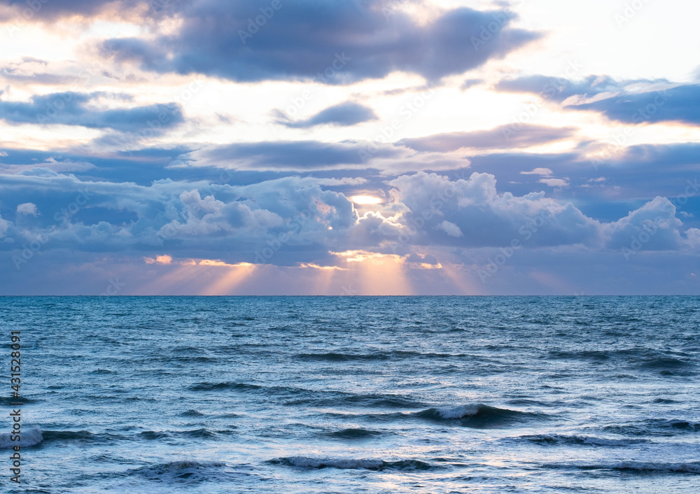 Fototapeta premium Sun breaking through the clouds over the sea