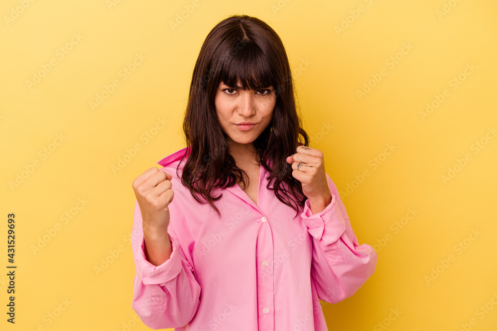 Young caucasian woman isolated on yellow background showing fist to camera, aggressive facial expression. Young caucasian woman isolated on yellow background showing fist to camera, aggressive facial expression.