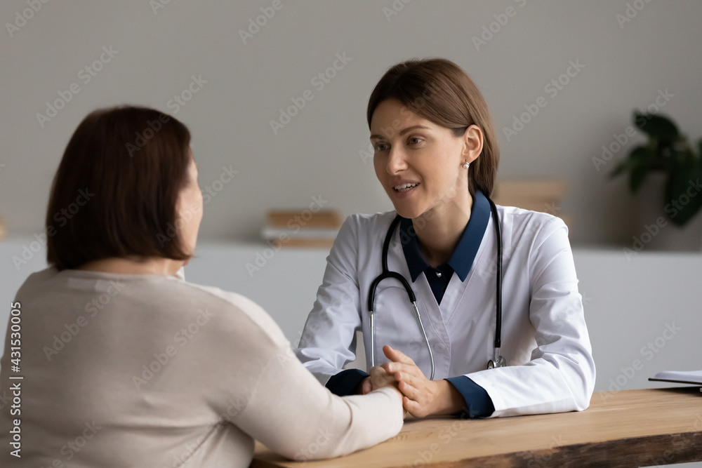Young Caucasian female doctor or therapist hold mature patient hands talk support at clinic meeting. Caring woman GP feel supportive caress comfort elderly client in hospital. Medicine concept. Young Caucasian female doctor or therapist hold mature patient hands talk support at clinic meeting. Caring woman GP feel supportive caress comfort elderly client in hospital. Medicine concept.