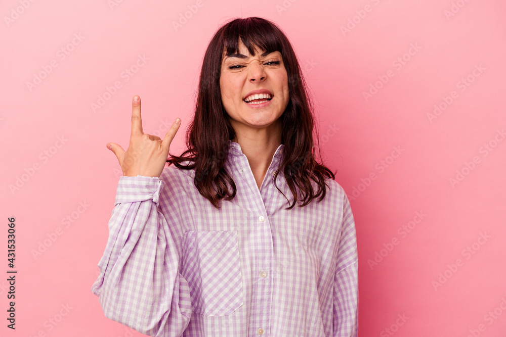 Young caucasian woman isolated on pink background showing rock gesture with fingers Young caucasian woman isolated on pink background showing rock gesture with fingers