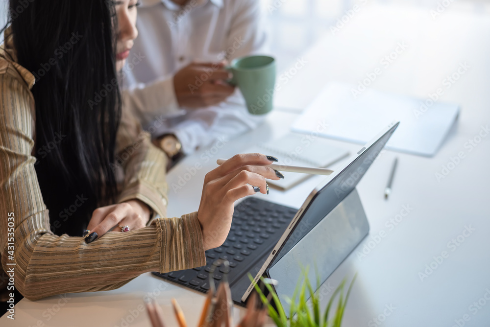 Side view of a businesswoman holding a pen using tablet working in office. Side view of a businesswoman holding a pen using tablet working in office.