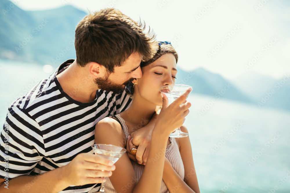 Beautiful couple having fun on the beach, drinking cocktails and smiling.