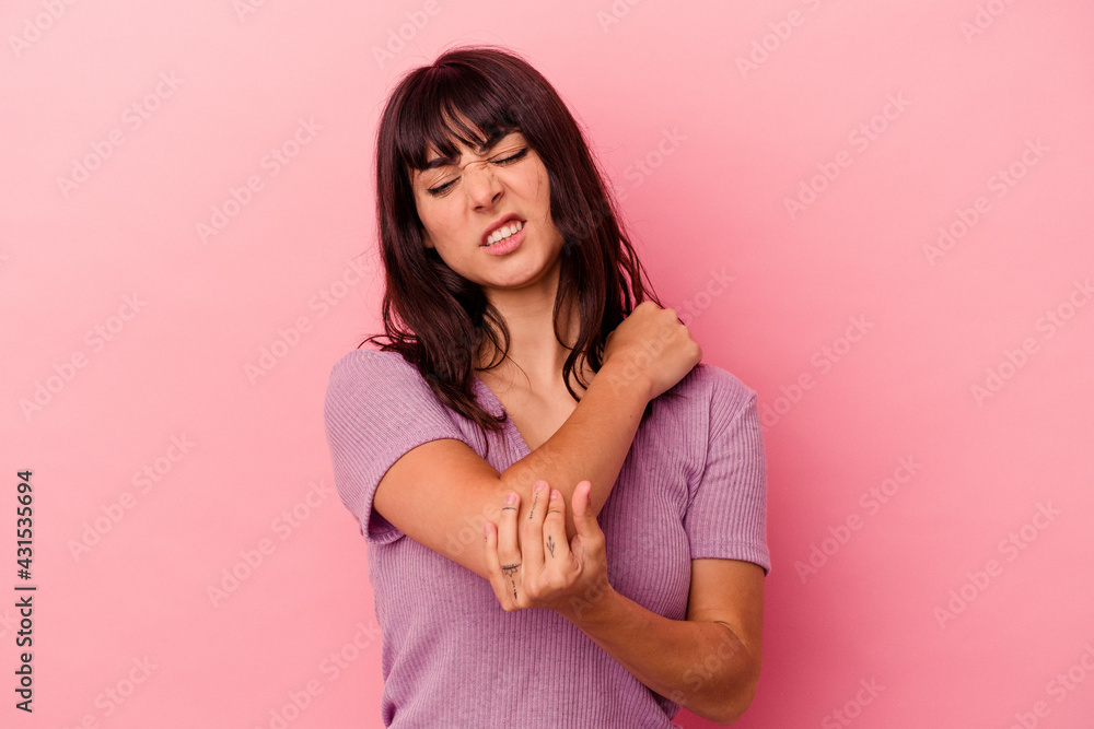 Young caucasian woman isolated on pink background massaging elbow, suffering after a bad movement. Young caucasian woman isolated on pink background massaging elbow, suffering after a bad movement.