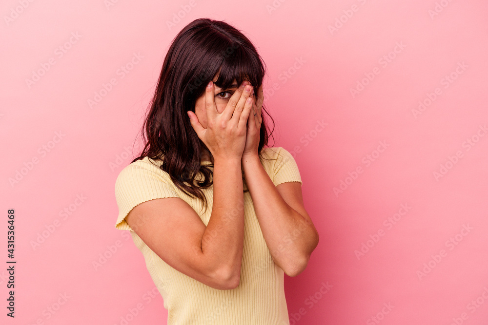Young caucasian woman isolated on pink background blink through fingers frightened and nervous. Young caucasian woman isolated on pink background blink through fingers frightened and nervous.