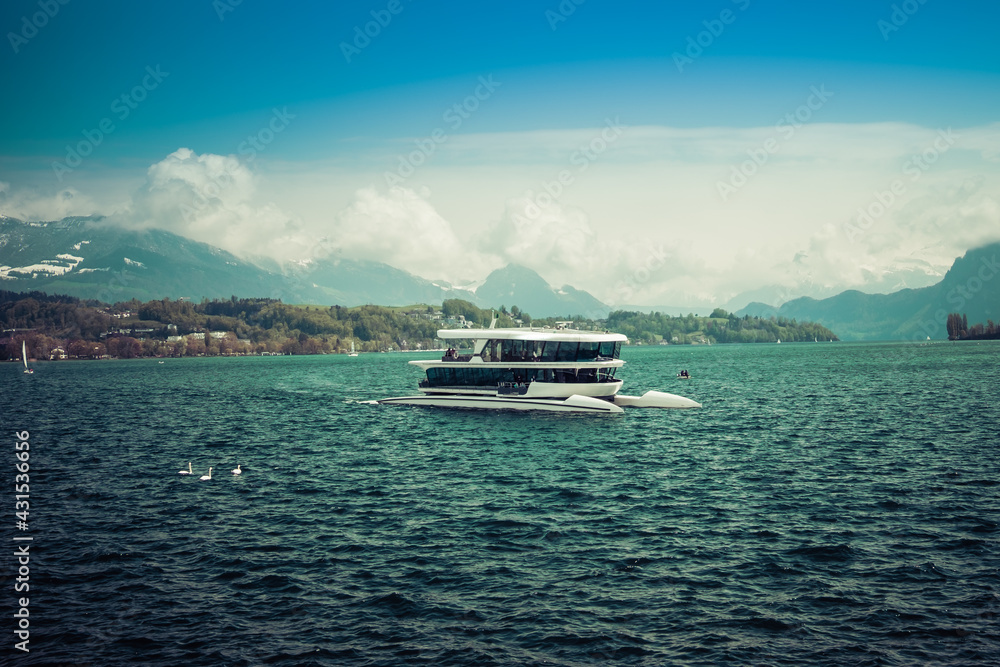 Futuristic boat on the lake of Luzern, with mountains and cloudy sky in the background, shot in Luzern, Switzerland