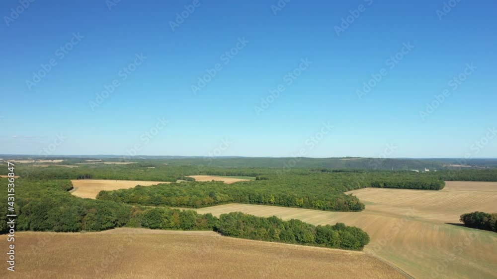 Les champs de blé après la moisson entourés de forêts verdoyantes  vers Nevers, dans la Nièvre, en Bourgogne, en France, à l'été, en drone sous un beau ciel bleu.