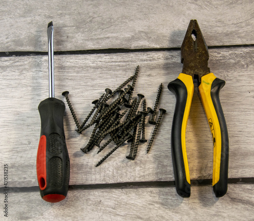 Black self-tapping screws, pliers, and a curly screwdriver.