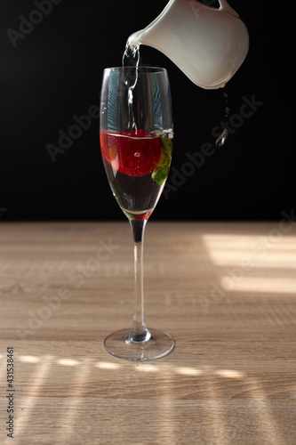 Ripe red strawberry in a glass of water. Splash in water on black background. Copy space