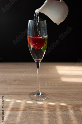 Ripe red strawberry in a glass of water. Splash in water on black background. Copy space