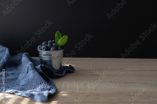 Fresh and sweet blueberry with mint in metal bucket on wooden table. Copy space.
