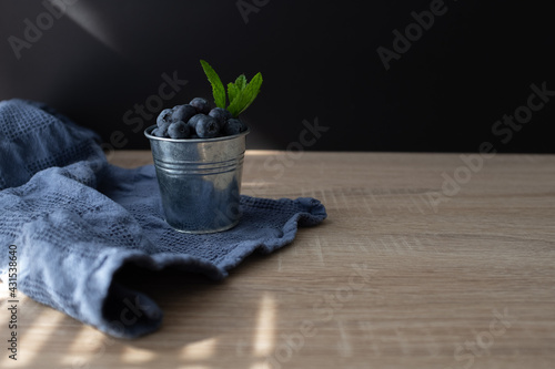 Fresh and sweet blueberry with mint in metal bucket on wooden table. Copy space.