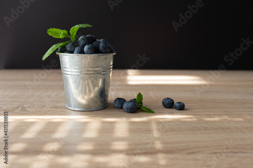 Fresh and sweet blueberry with mint in metal bucket on wooden table. Copy space.